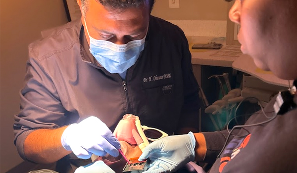 Pediatric dentist examines young patient's teeth during dental appointment in clinical setting.