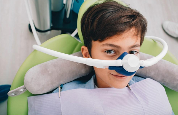 Young boy in dental chair wearing protective eyewear during orthodontic examination at pediatric dental office.