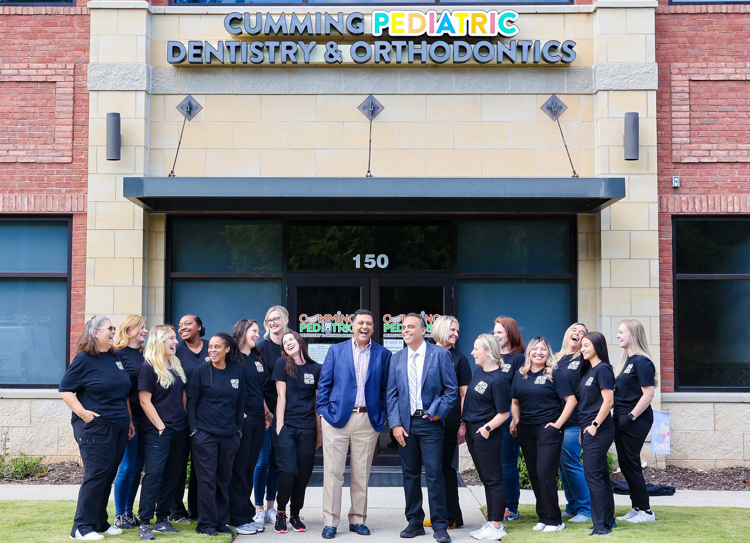 Team of dental professionals standing together outside Cumming Pediatric Dentistry & Orthodontics office building.