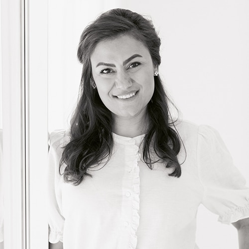 Professional headshot of smiling woman in white shirt against plain background